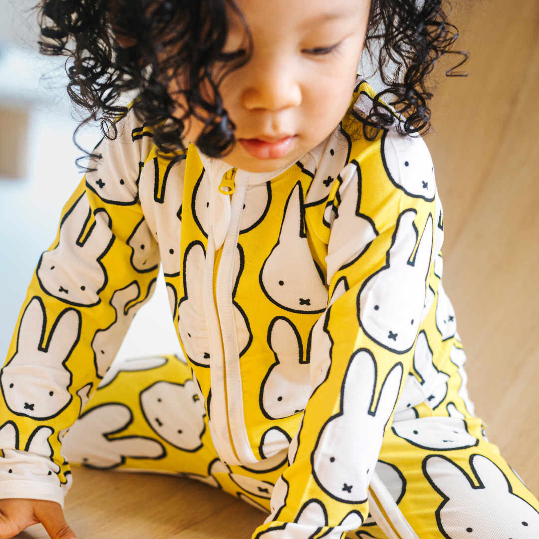 Baby klädd i ZIPSTER x Miffy Hello Yellow bambu-babyoverall